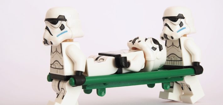 Deux stormtroopers en portent un troisième sur un brancard.